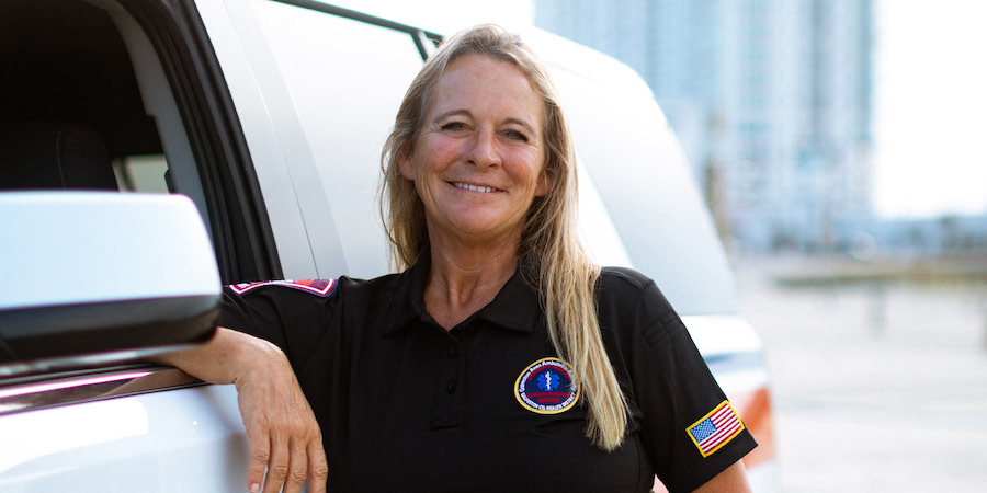 image of Amy Weber, director of EMS for Galveston County Health District in uniform leaning against vehicle with open window