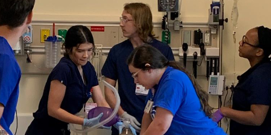 image of students collaborating on emergency patient in a simulated hospital setting