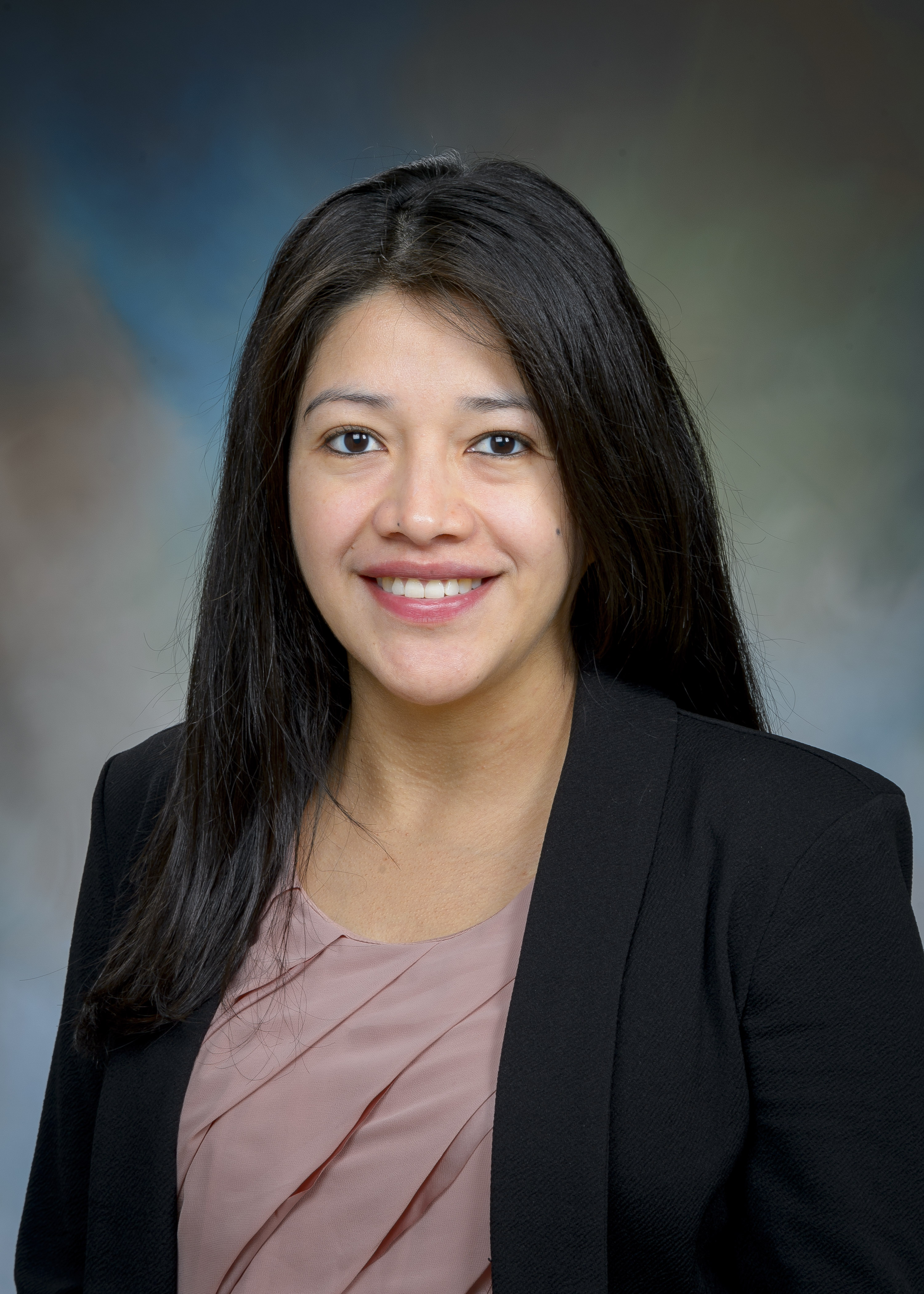 headshot image of latina woman wearing a mauve shirt with a black blazer. she has black hair down to her chest and is smiling 