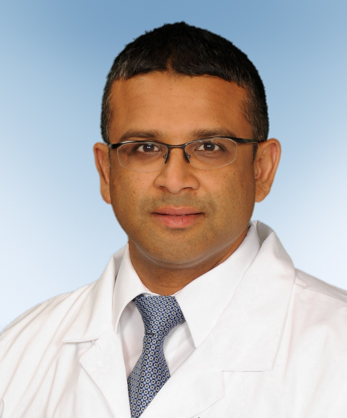 male physician headshot - he's wearing glasses, a tie and a white coat 