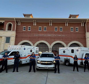 image of Galveston County Health District medic team standing in front of fire station and emergency response vehicles