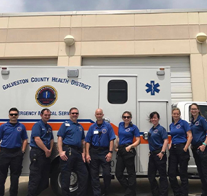 image of Galveston County Health District medic team members standing in uniform in front of an ambulance