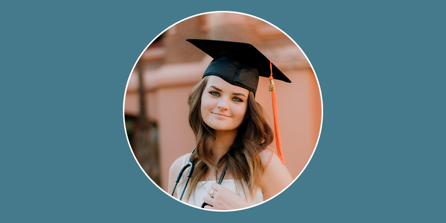 graduation headshot of Emiley Goodrich wearing a white top, black graduation cap with a red tassel, and a stethoscope around her neck.