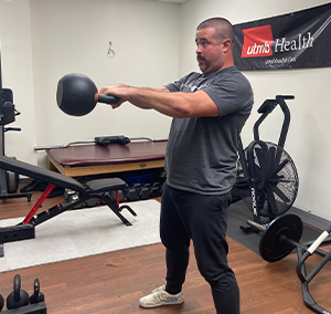 image of Tyler Morrison swinging dumbbell forward