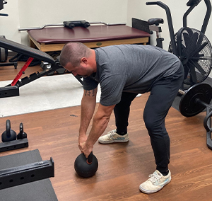 image of man bending over to grab a kettlebell
