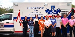 nine people standing in front of an ambulance
