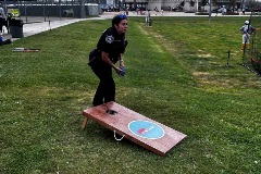officer playing cornhole  game at youth baseball event