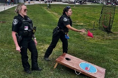 officers playing cornhole game at youth baseball event