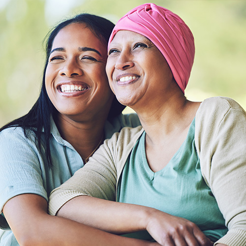 A woman with a pink head scarf is embraced by her adult daughter.