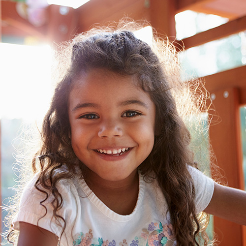 A young girl happily playing on a playground outside.