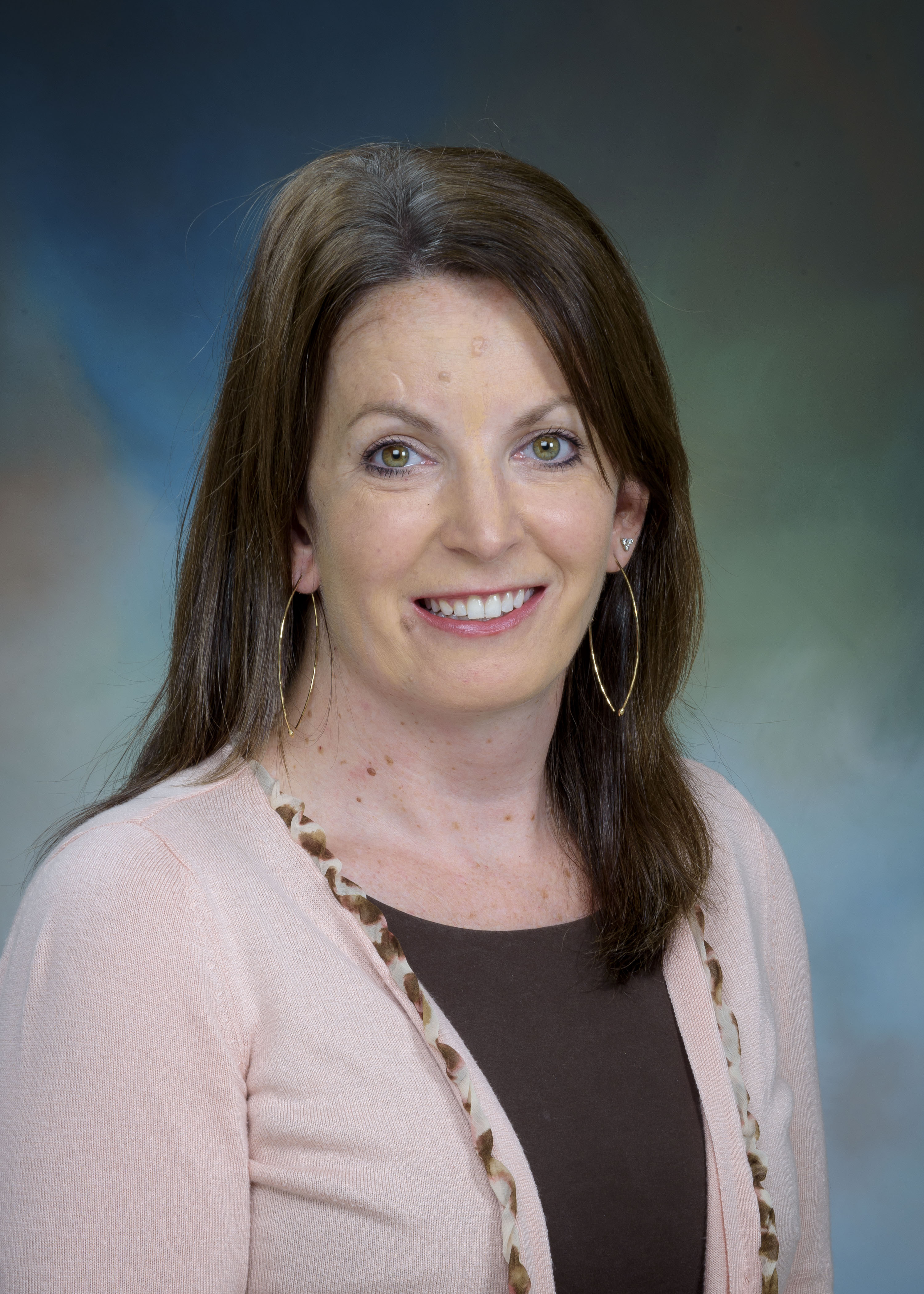 Dr. Barbara Calvert headshot image of clinical psychologist Dr. Barbara Calvert - a female clinician wearing a brown shirt with a pink cardigan and gold earrings