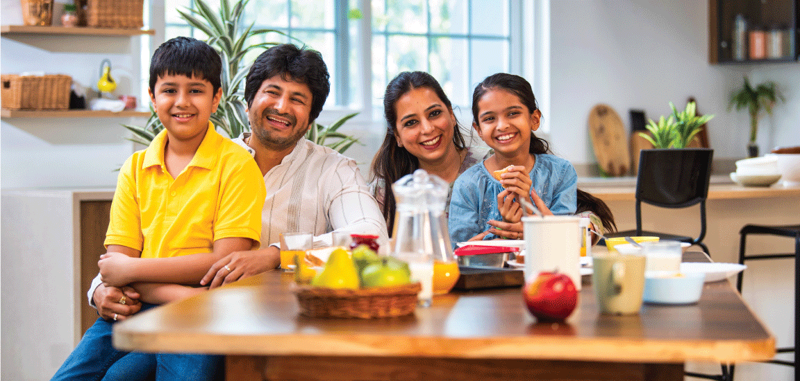 family at kitchen breakfast table with fruit and juice