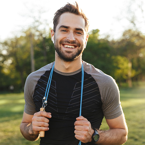 A young, fit man wearing exercise gear smiles.