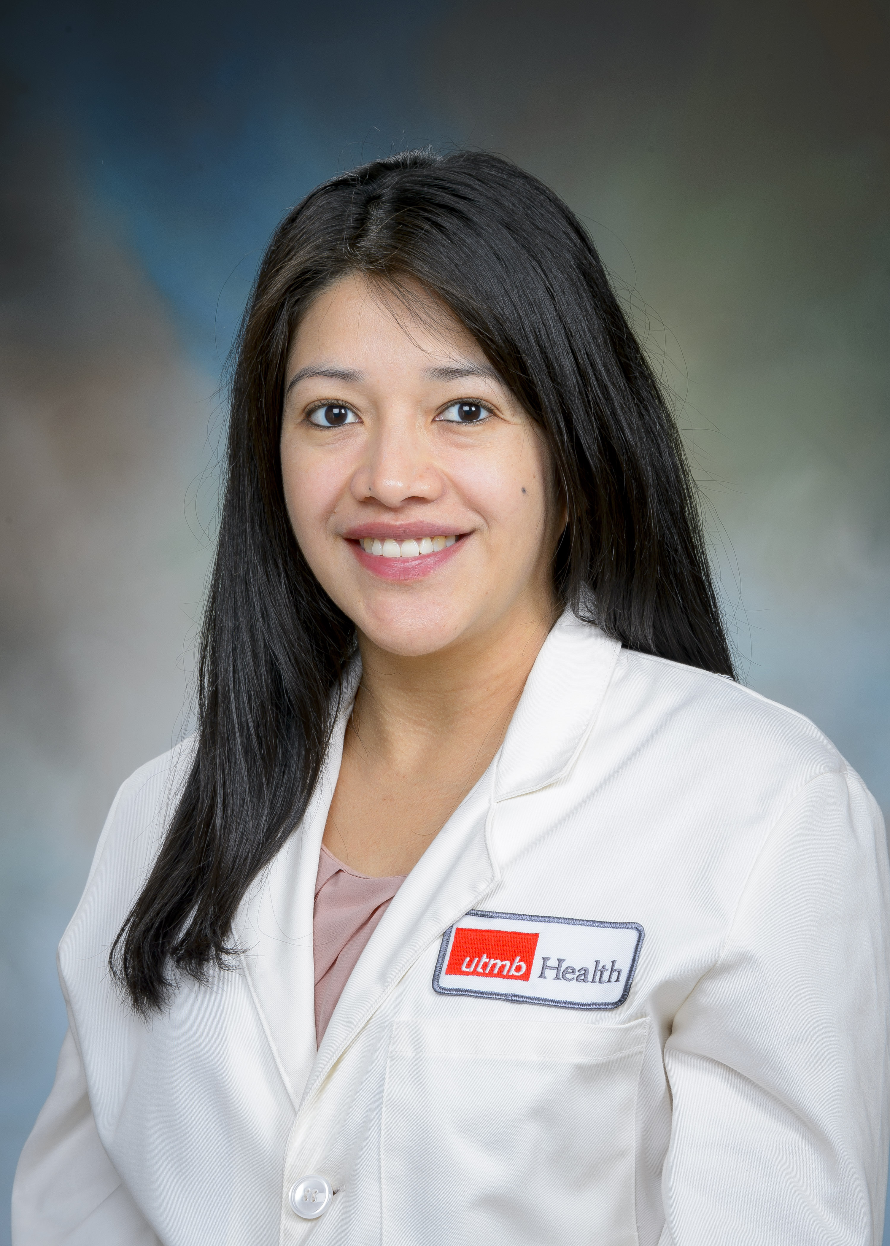 headshot image of utmb health pediatric surgeon dr. maria carmen mora - she is wearing a white coat over a blush colored top and has chest-length black hair split down the middle