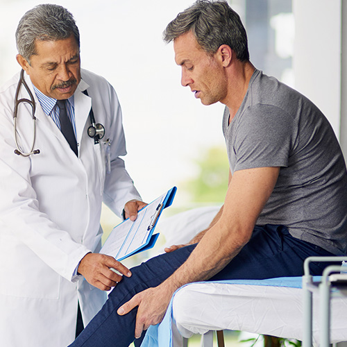 A doctor examines a man's knee.
