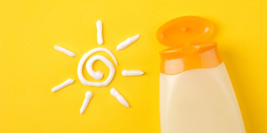 graphic with yellow background and white sun drawn in sunscreen next to a sunscreen bottle