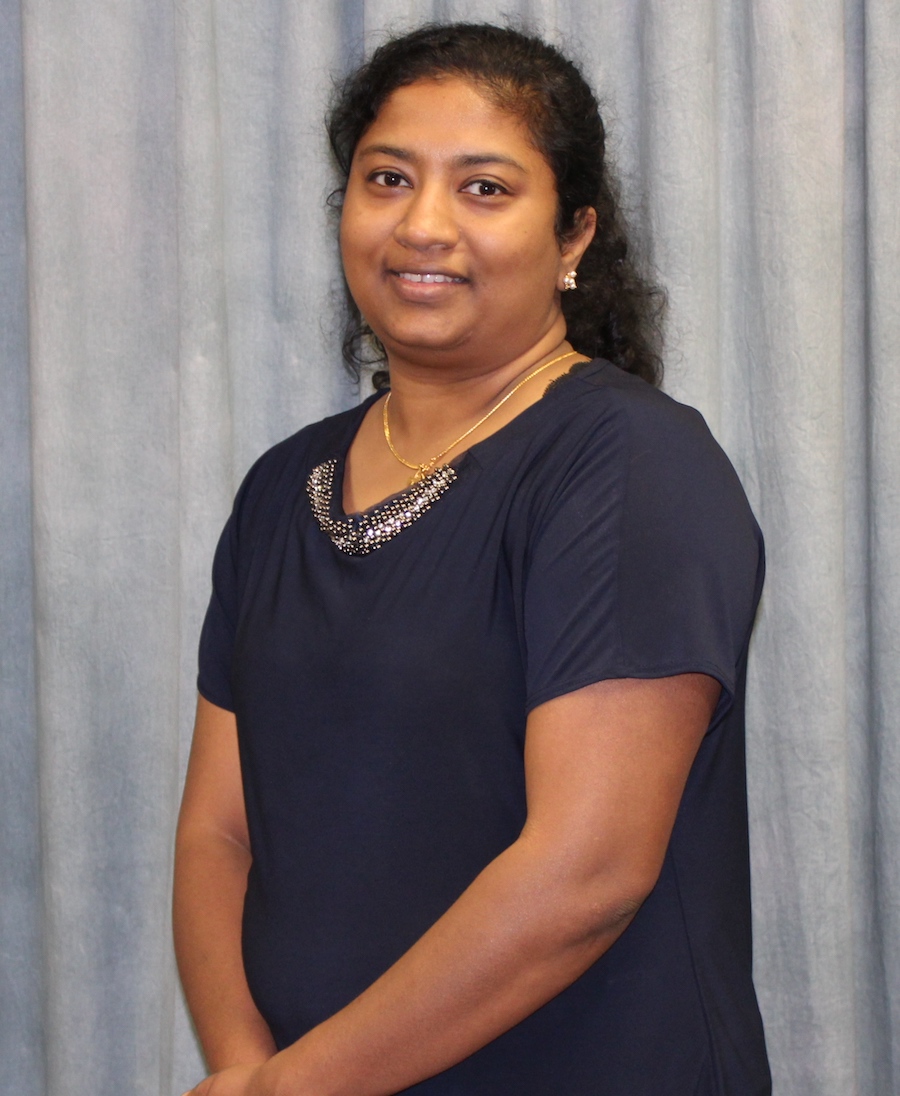 headshot image of female wearing navy blouse smiling in front of backdrop