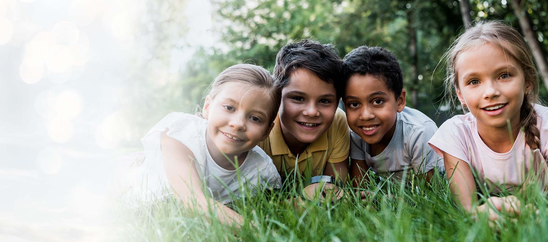 Children smiling, laying in a field