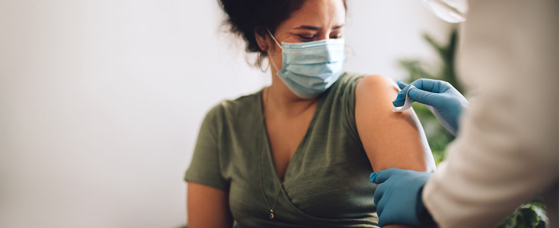 Masked woman getting arm swabbed by doctor