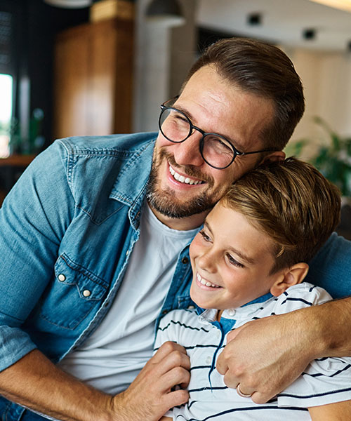 A dad and son happily embrace in a hug