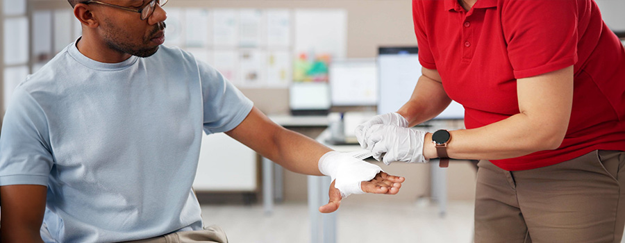A UTMB medical provider applies a bandage to a patient's hand during burn wound care.