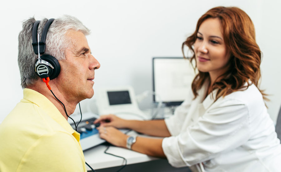Female doctor, otolaryngologist, conducting hearing test on elderly man in office