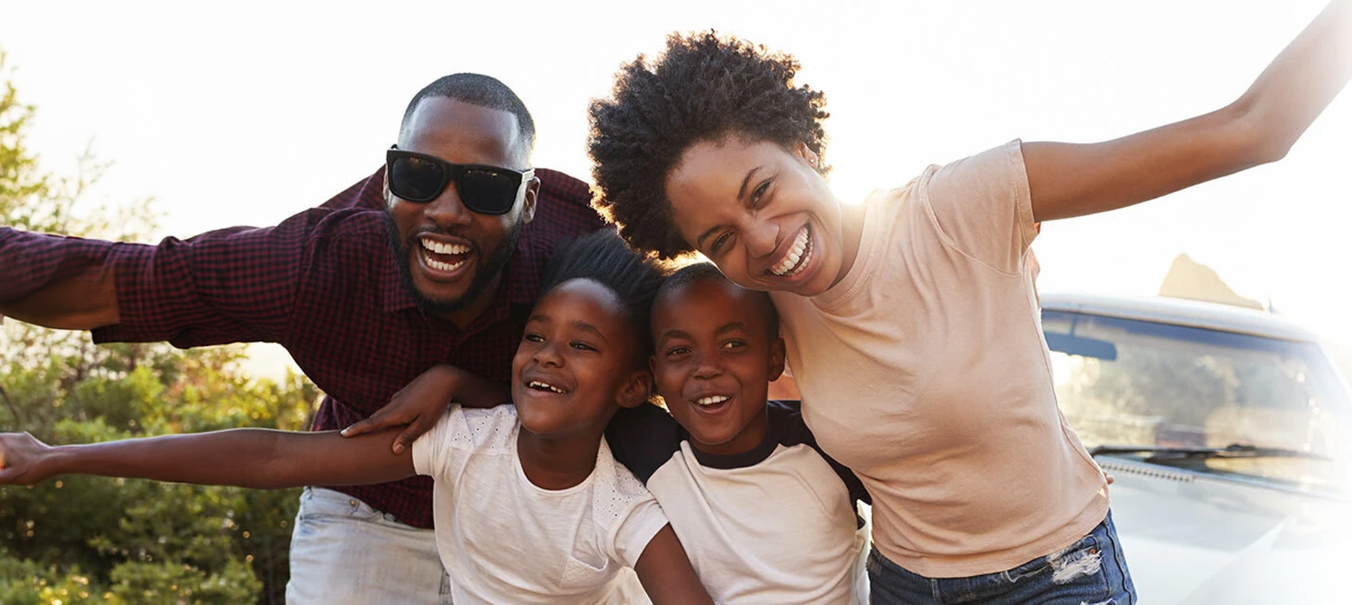 Happy, Black family – man in sunglasses, a woman, and two young children enjoying the outdoors