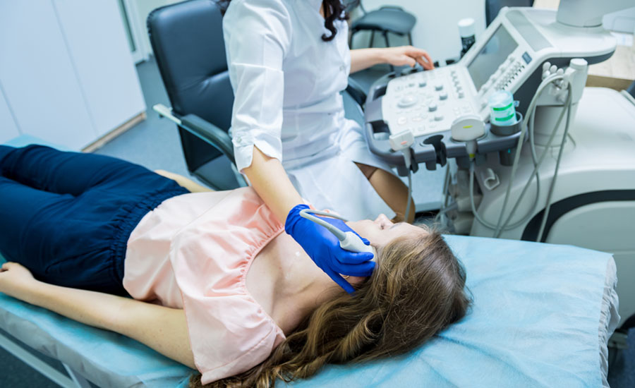 Female doctor using ultrasound scanning machine to examine a female patient’s head