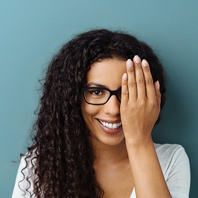 woman wearing glasses with one hand over eye