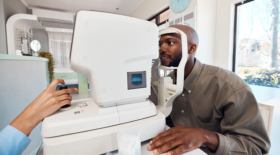 Eye test, exam or screening with a young man at the optometrist using an automated refractor.