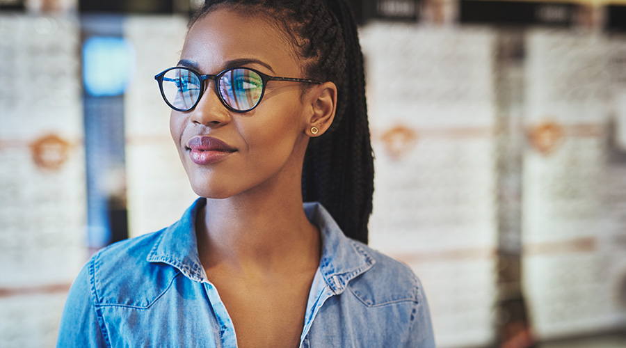 A woman wearing glasses stands in an optical retail center at UTMB.