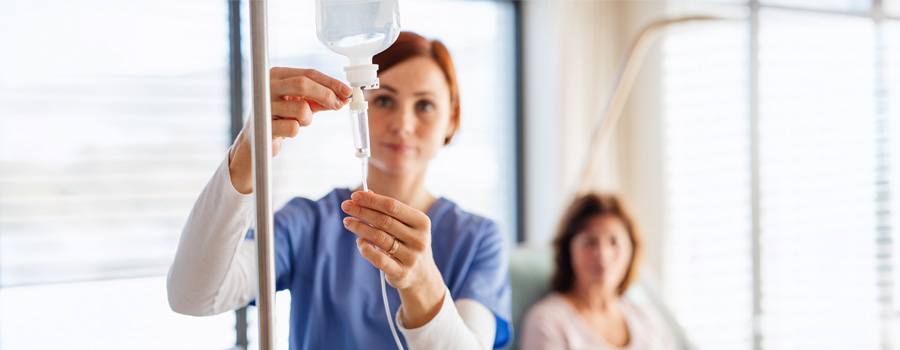 A nurse prepares an IV infusion while a patient receives treatment for a genetic condition at UTMB Health.