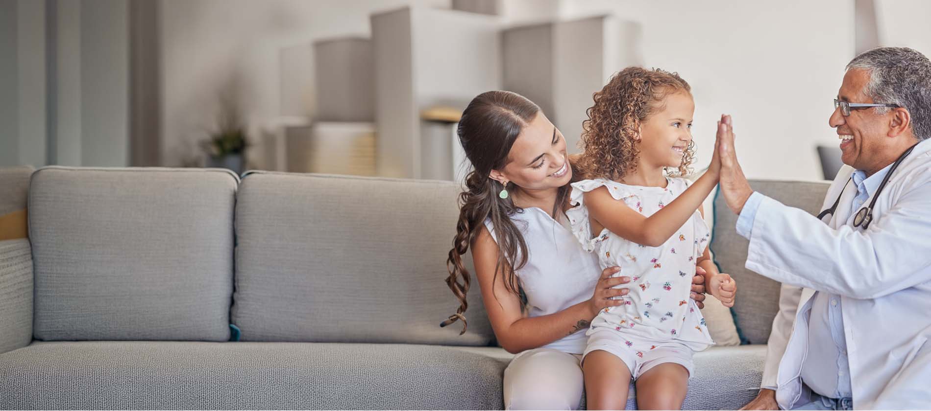 A genetics specialist high fives a young patient while speaking with her parent during a genetic consultation at UTMB Health.