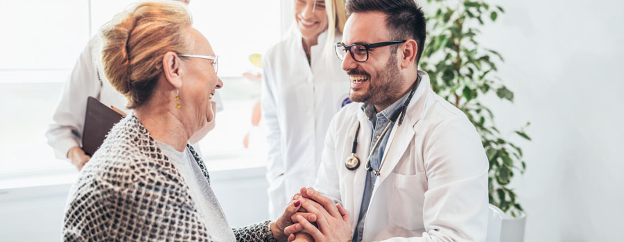 A physician holds an older patients hands while discussing genetic health and medical genetics care at UTMB Health.