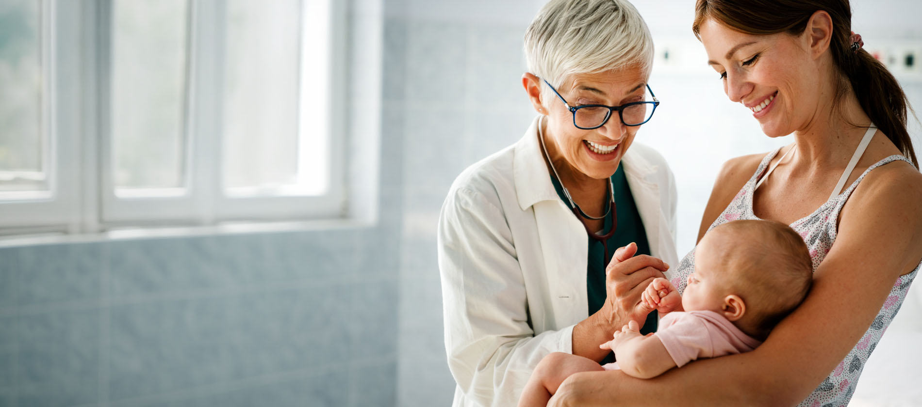 A physician examines a newborn while speaking with a parent during a medical genetics evaluation at UTMB Health.