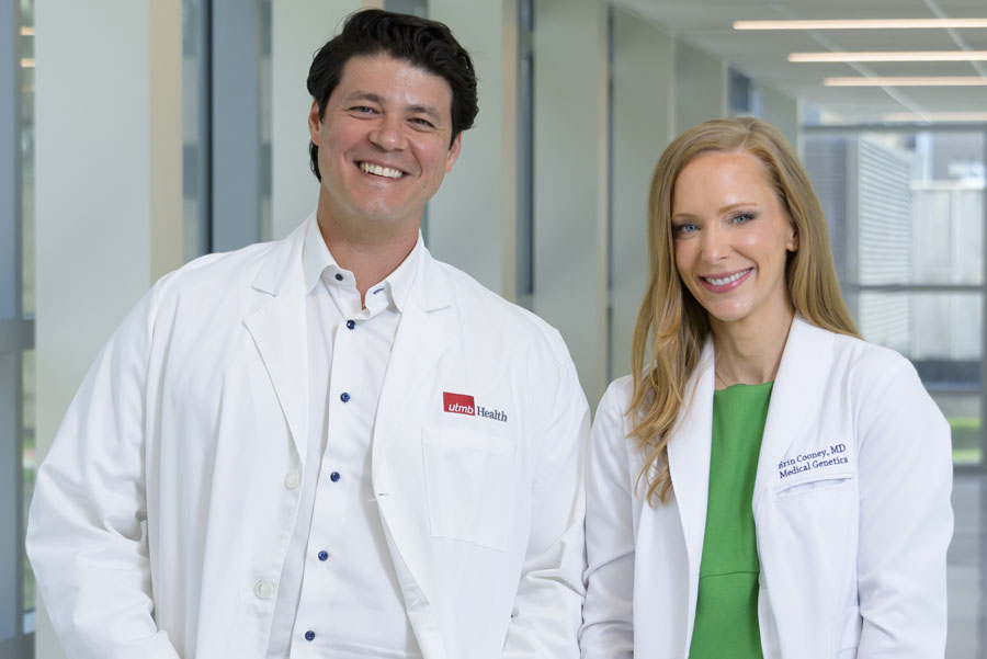 Two UTMB Health physicians, Dr. Erin Cooney and Dr. Joseph Ray, stand together in a bright hallway leading UTMB’s Gene Therapy Program.