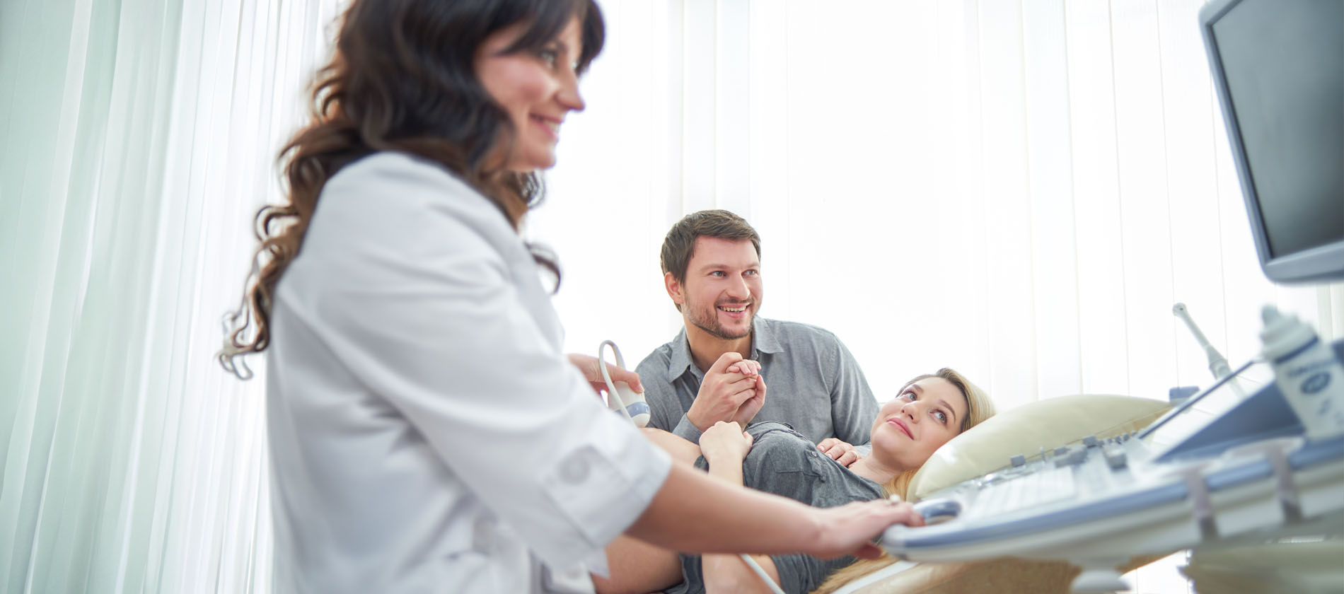 A clinician performs an ultrasound exam while discussing prenatal genetic evaluation with expecting parents at UTMB Health.