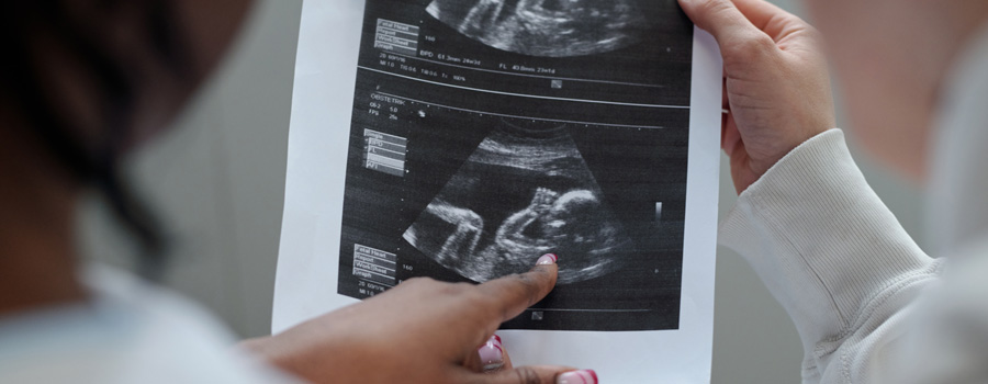 A clinician reviews ultrasound images with a patient while discussing prenatal genetic screening results at UTMB Health.
