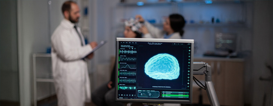 A computer screen displays brain wave activity during a neurodiagnostic test, while a clinician prepares a patient for EEG monitoring in the background.