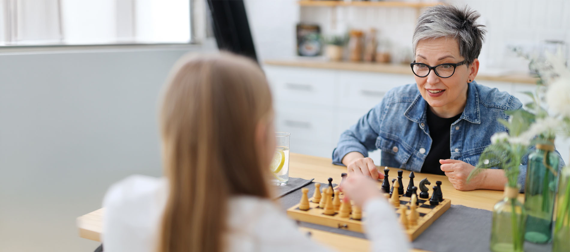 An older adult plays a game of chess with another person showing focus engagement and cognitive activity.