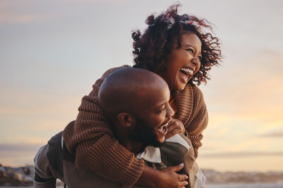 Two adults laugh together outdoors representing connection emotional wellbeing and quality of life while living with neuroimmunologic conditions.