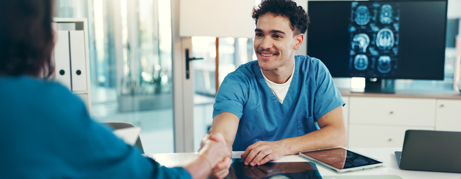 A neurologist and patient shake hands during a clinic visit for movement disorder care and treatment planning.