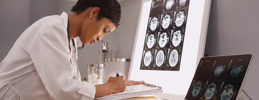 A neurologist reviews brain imaging while documenting findings during a stroke and vascular neurology evaluation.