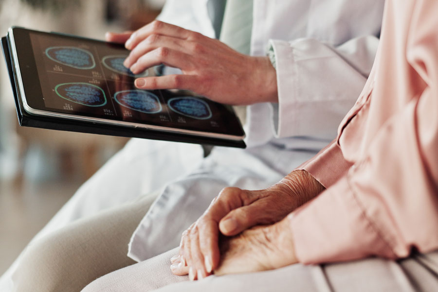 A provider reviews brain scan images on a tablet with a patient during neurosurgery diagnostic testing at UTMB Health.