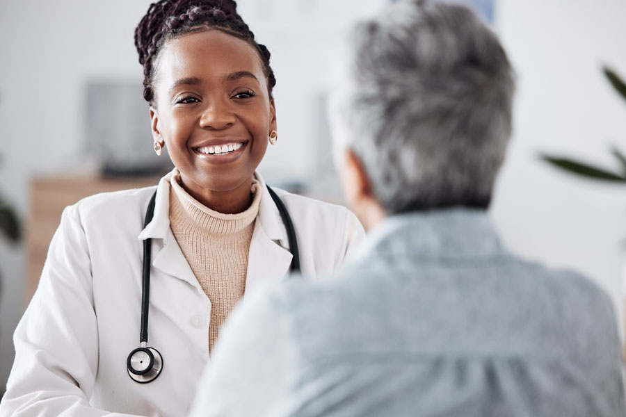 A neurosurgery specialist speaks with an older adult during a consultation for trigeminal neuralgia and facial pain at UTMB Health.