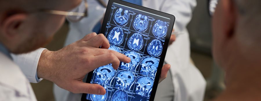 A neurosurgery provider reviews brain imaging on a tablet while discussing trigeminal neuralgia treatment options at UTMB Health.