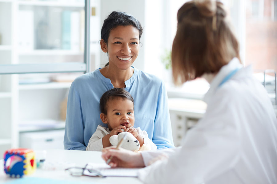 A pediatric neurosurgery provider meets with a caregiver and infant in a calm and supportive clinic setting at UTMB Health.