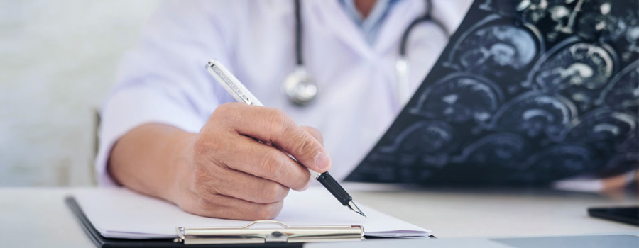 A provider reviews brain imaging and notes while planning pediatric neurosurgery care at UTMB Health.