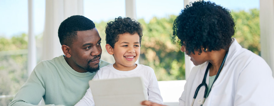 A pediatric neurosurgeon reviews care information with a parent and child during a supportive visit at UTMB Health.