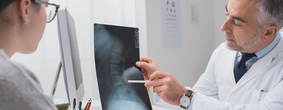 A neurosurgeon explains spine imaging results to a patient during a consultation for back and neck pain at UTMB Health.